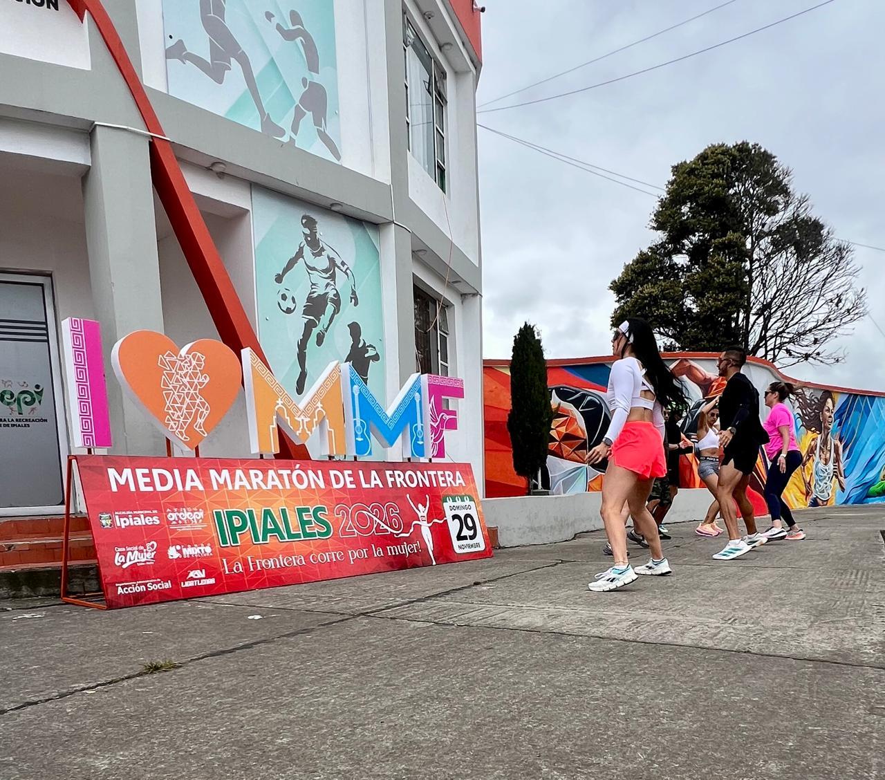 Corredores frente al cartel de la carrera en la sede de Ordepi